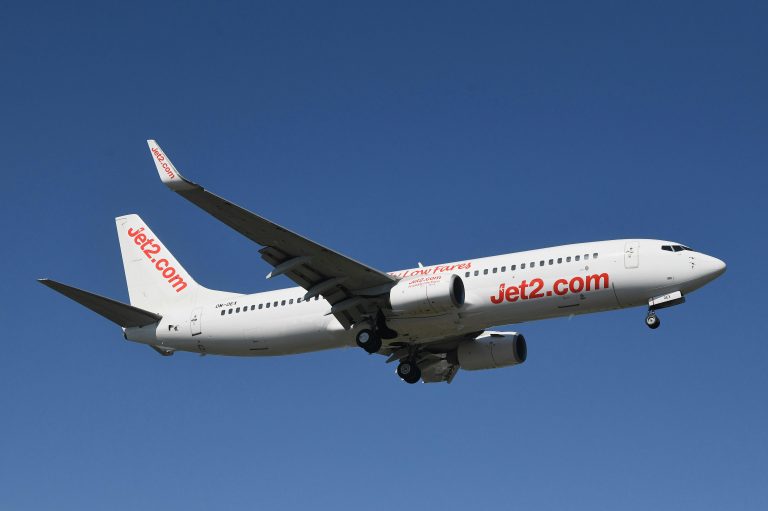 Jet2 Boeing airplane flying over Geneva with clear blue sky backdrop.