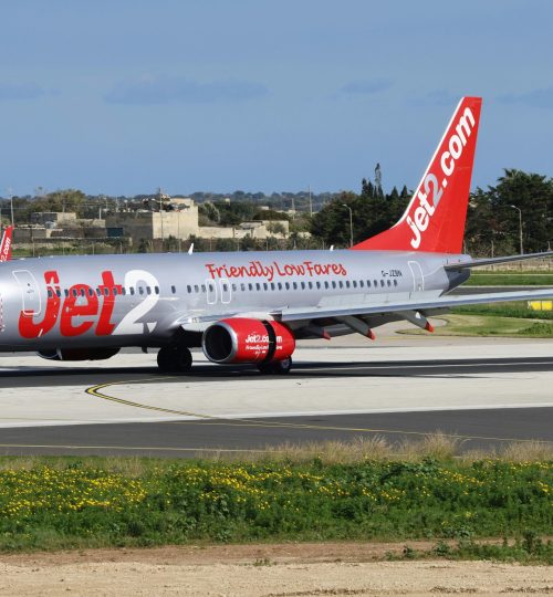 Jet2 airplane on airport tarmac with clear blue sky, showcasing travel and transportation.